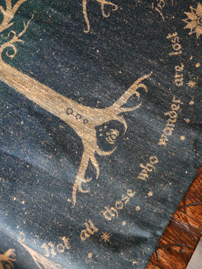 Decorative fabric with gold embroidery of a tree and text on a dark background