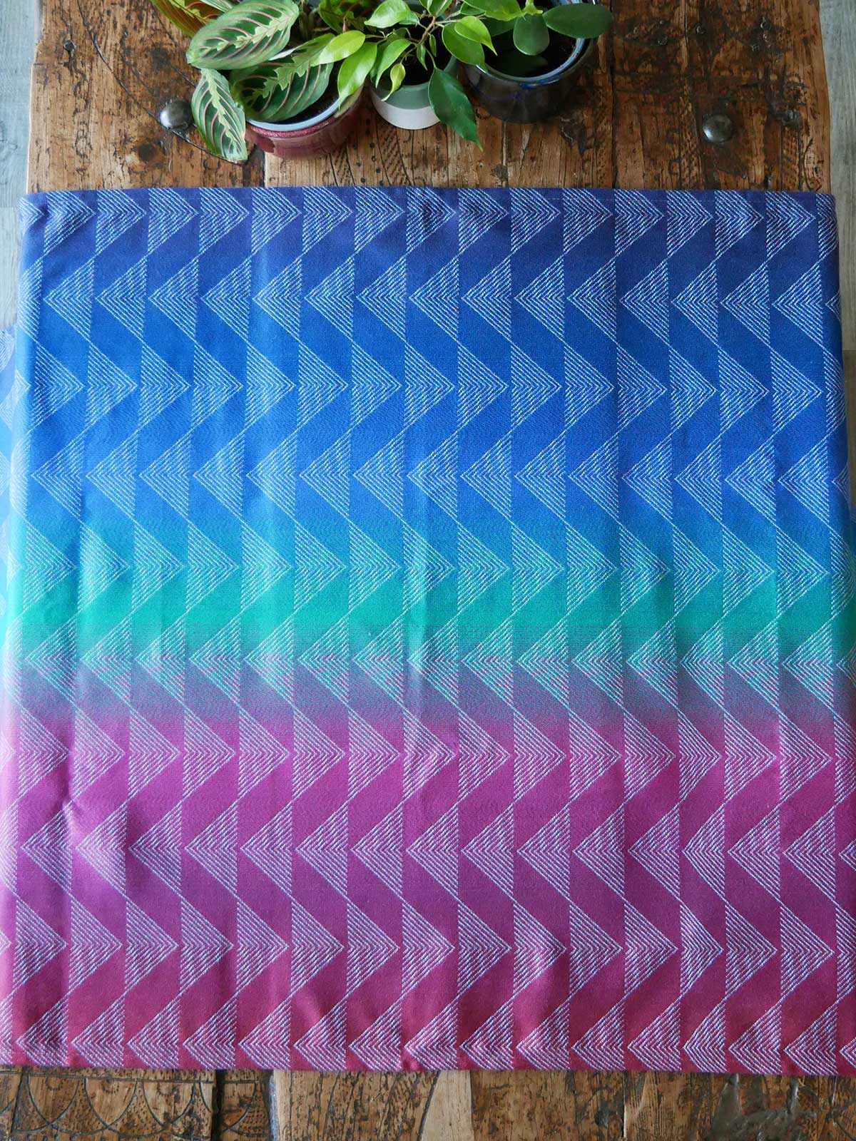 Gradient fabric with blue, green, and pink pattern on a wooden surface