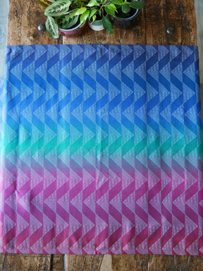 Gradient fabric with blue, green, and pink pattern on a wooden surface