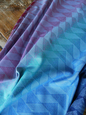 Close-up of fabric with blue and purple geometric pattern on a wooden surface