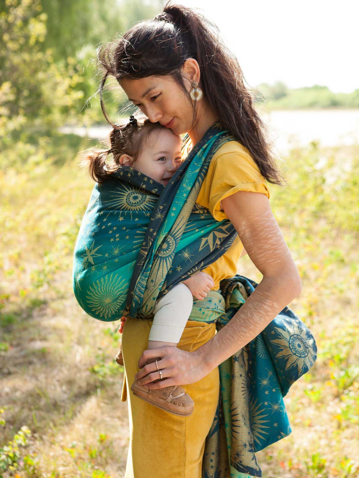 Side view of a woman carrying a child on her front in a eal woven wrap with starry pattern