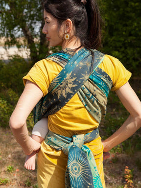 Rear view of a woman carrying a child on her front in a eal woven wrap with starry pattern