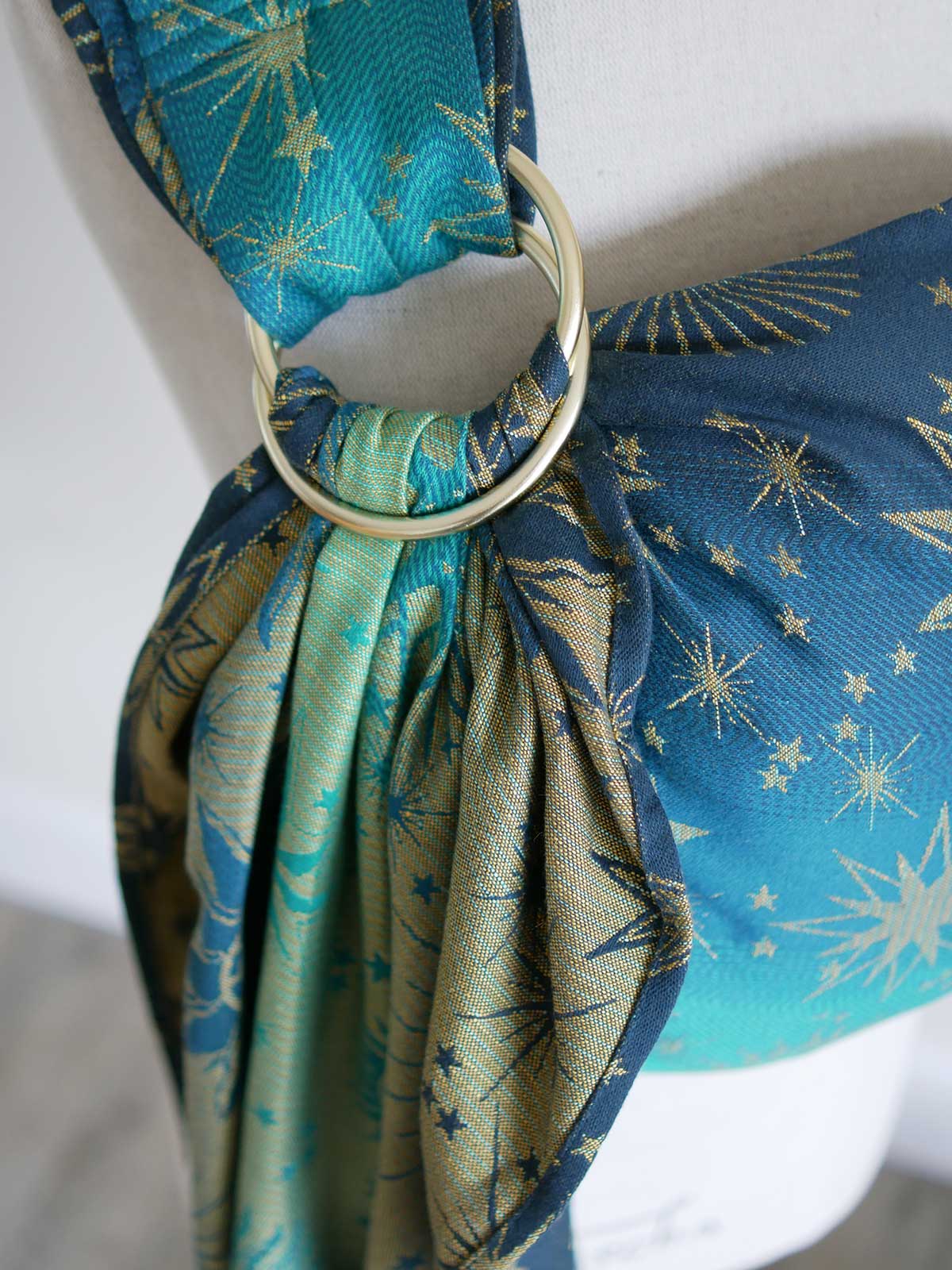 Close up of gold ring on a teal ring sling with starry pattern on a mannequin
