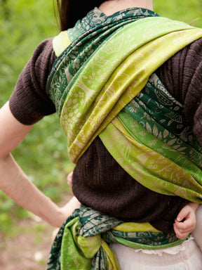 Back of a woman wearing a woven wrap with animal folk design.