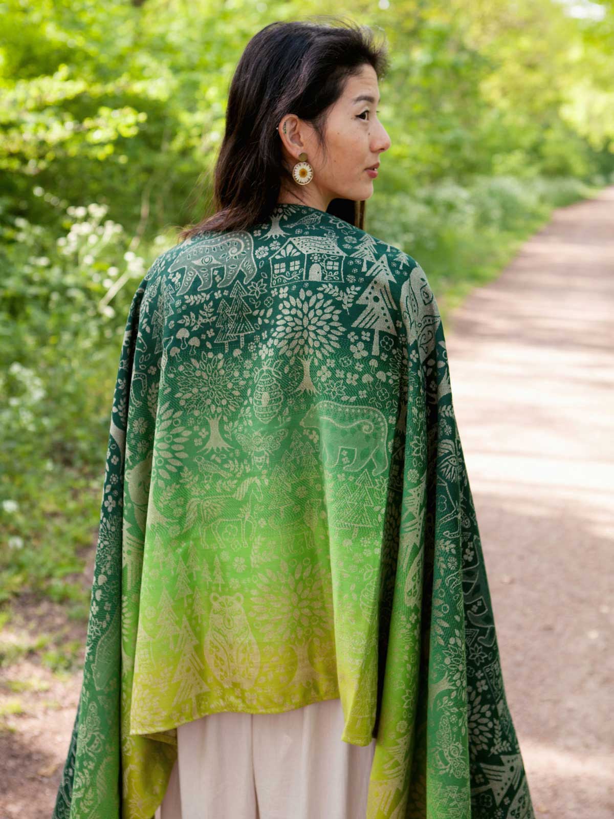 Woman wearing a green woven wrap with animal folk design.