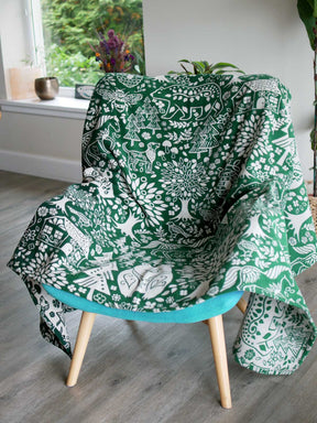Green throw with folk art design draped over a chair.