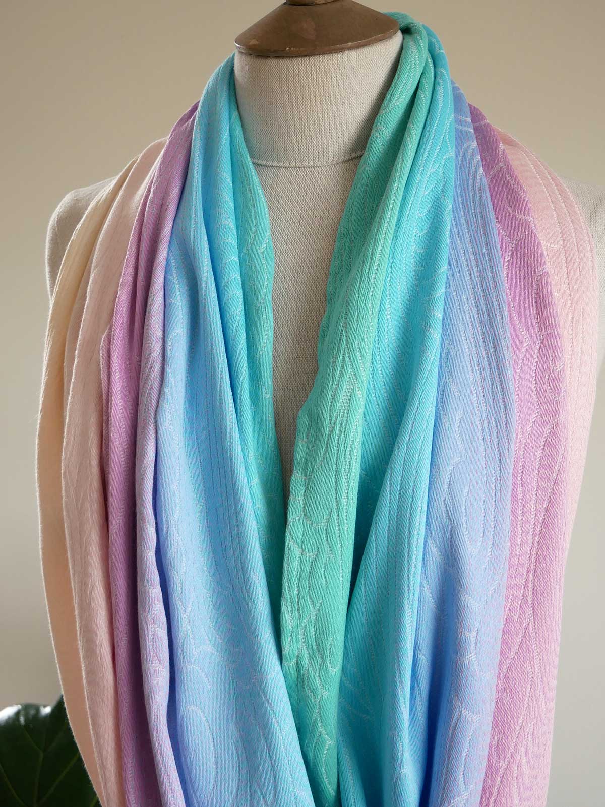 Pastel colored infinity loop scarf on a mannequin against a neutral background