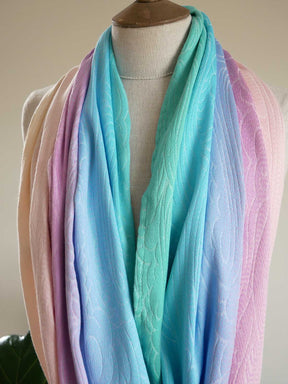 Pastel colored infinity loop scarf on a mannequin against a neutral background