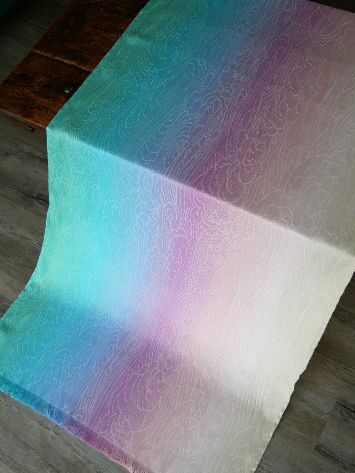 Gradient fabric with blue, green, and purple colors on a wooden surface