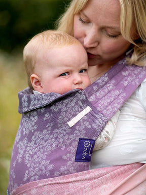 Close up of baby in Oscha carrier with floral pattern. 
