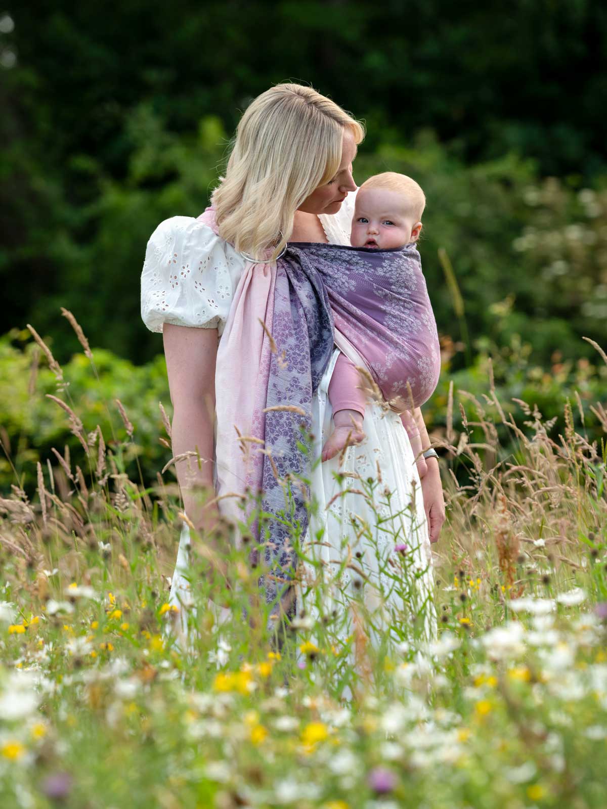 Side view of model in purple and pink toned baby ring sling. 