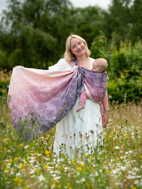 Model holding out fabric showing tail of beautiful ring sling. 