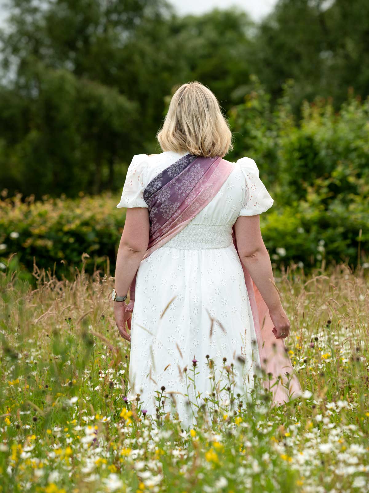 Back view of model in white dress wearing a ring sling. 