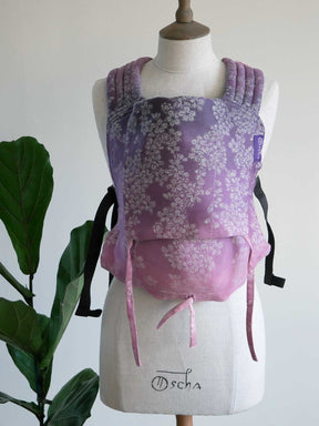 Purple floral baby carrier on a mannequin with a plant in the background