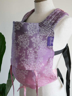 Purple floral baby carrier on a mannequin with a visible brand label.