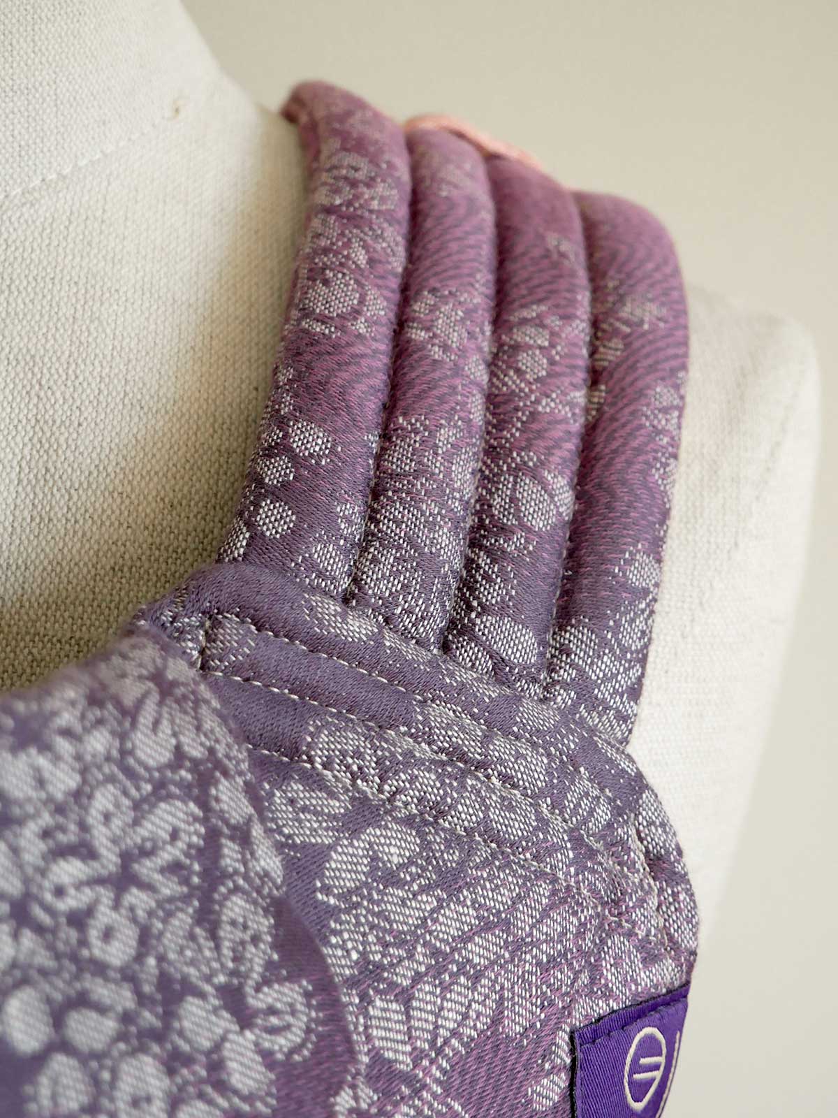 Purple baby carrier strap on a mannequin arm against a neutral background