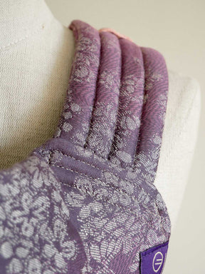 Purple baby carrier strap on a mannequin arm against a neutral background