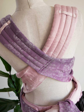 Pink and purple baby carrier on a mannequin with a plant in the background