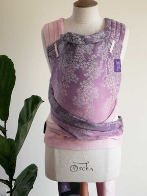 Purple baby carrier with floral pattern on a mannequin against a white background