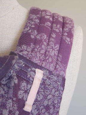 Close-up of a purple fabric with floral pattern on a mannequin.