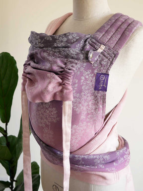 Purple baby carrier on a mannequin with a plant in the background