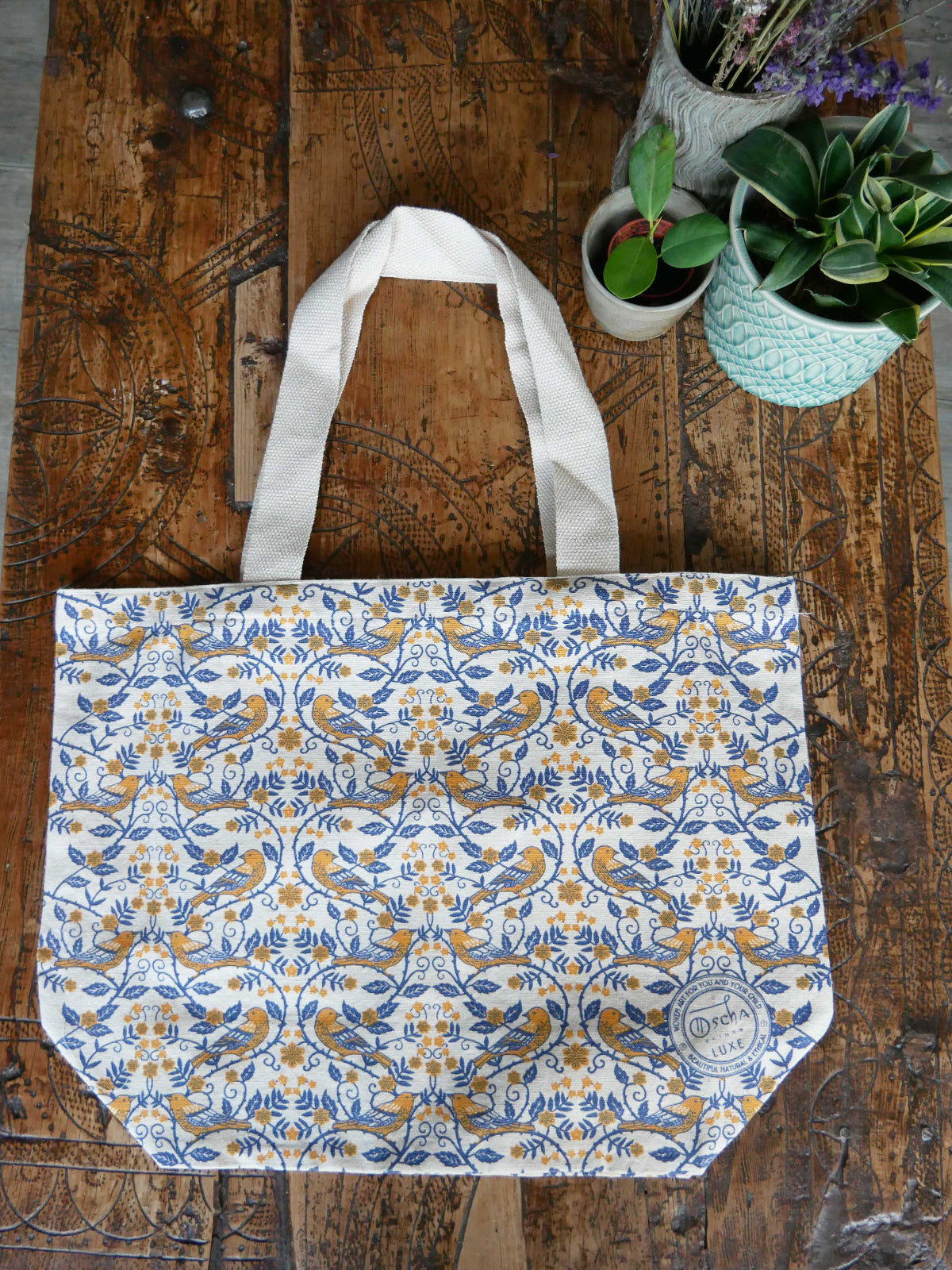 Patterned tote bag on a wooden surface with plants in the background