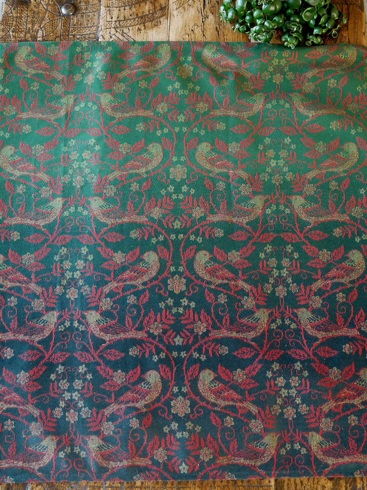 Patterned fabric with birds and floral designs on a wooden surface