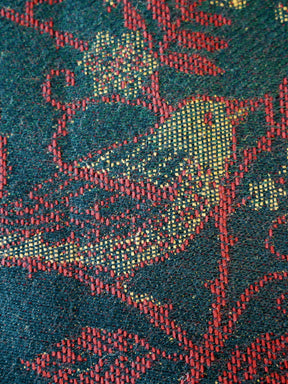 Close-up of a textured fabric with red and green patterns on a dark background