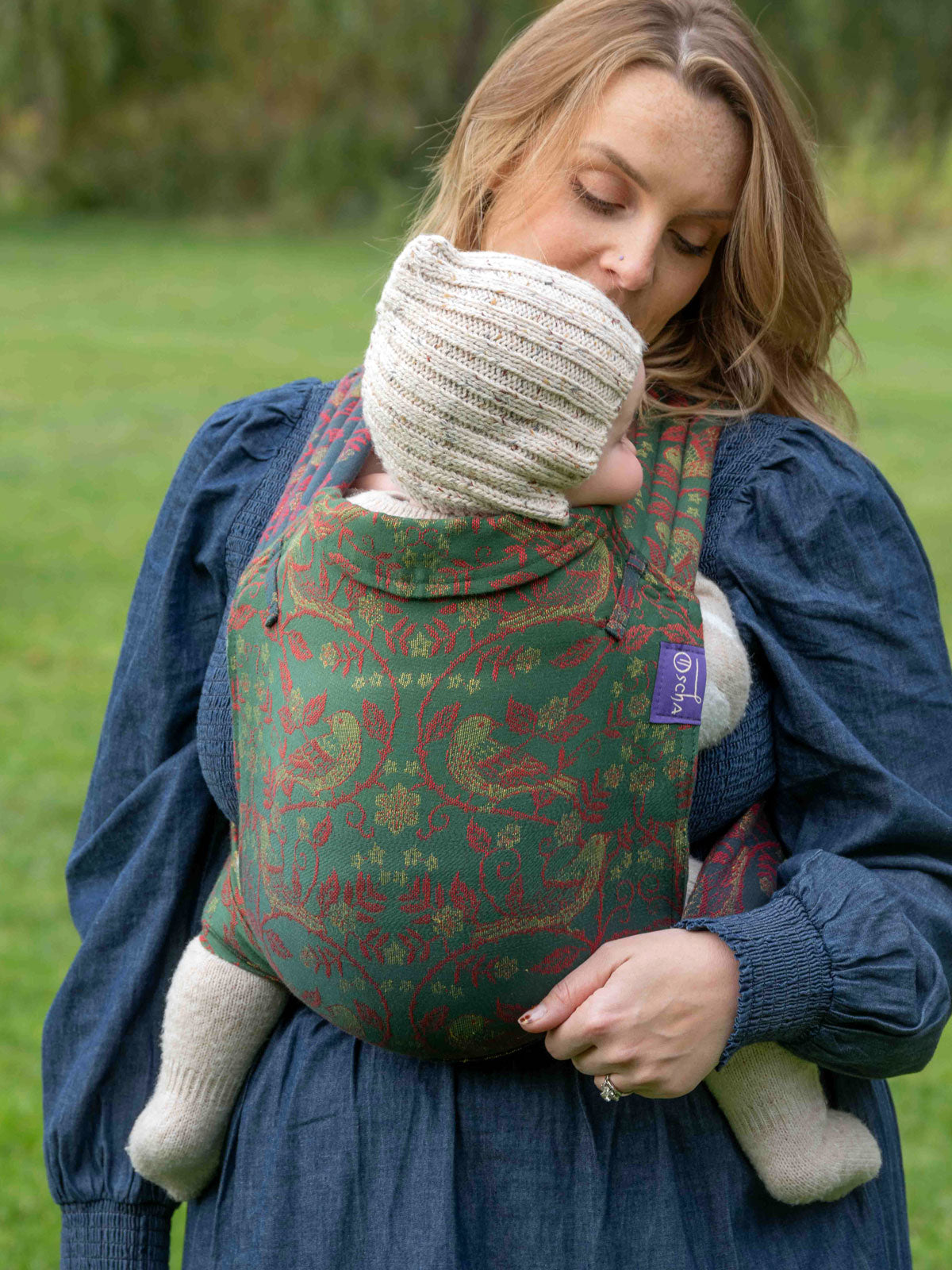 Woman carrying a child in a Briarwood Winter's Song Cairis Baby Carrier outdoors