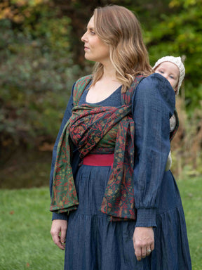 Woman wearing a blue dress with a patterned baby carrier outdoors