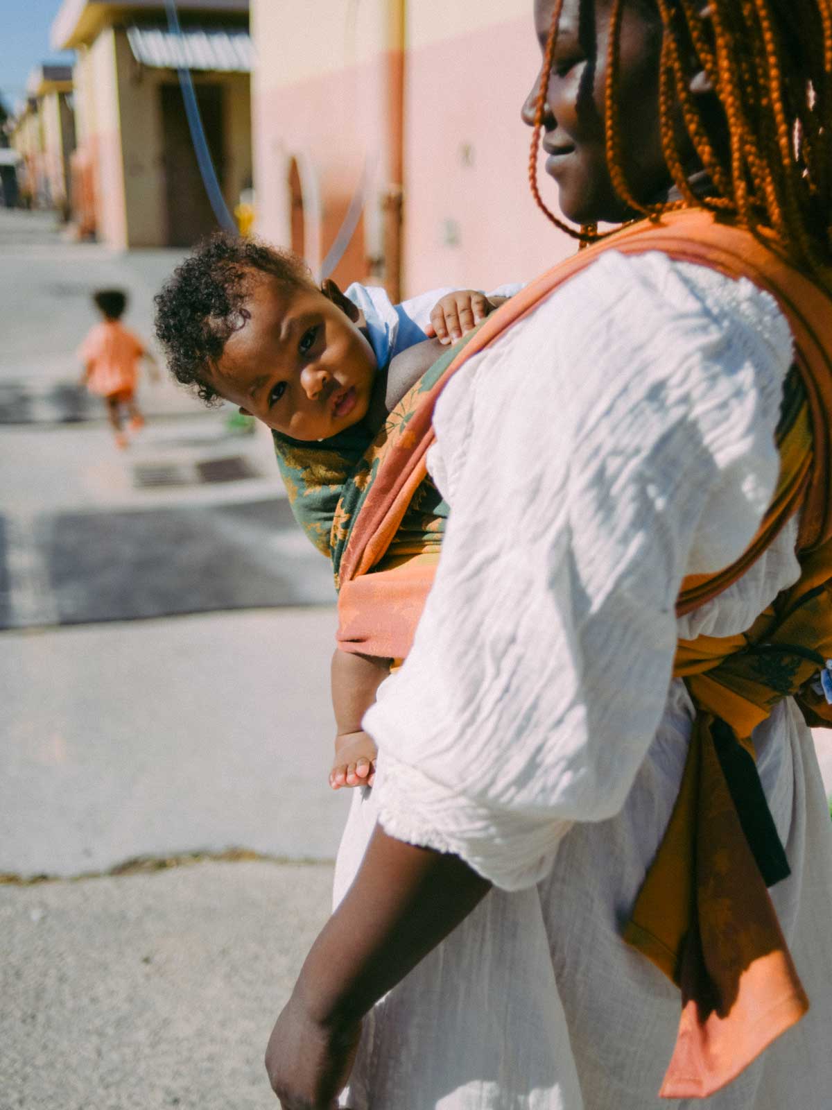 Woman carrying a child in a baby wrap in an urban setting
