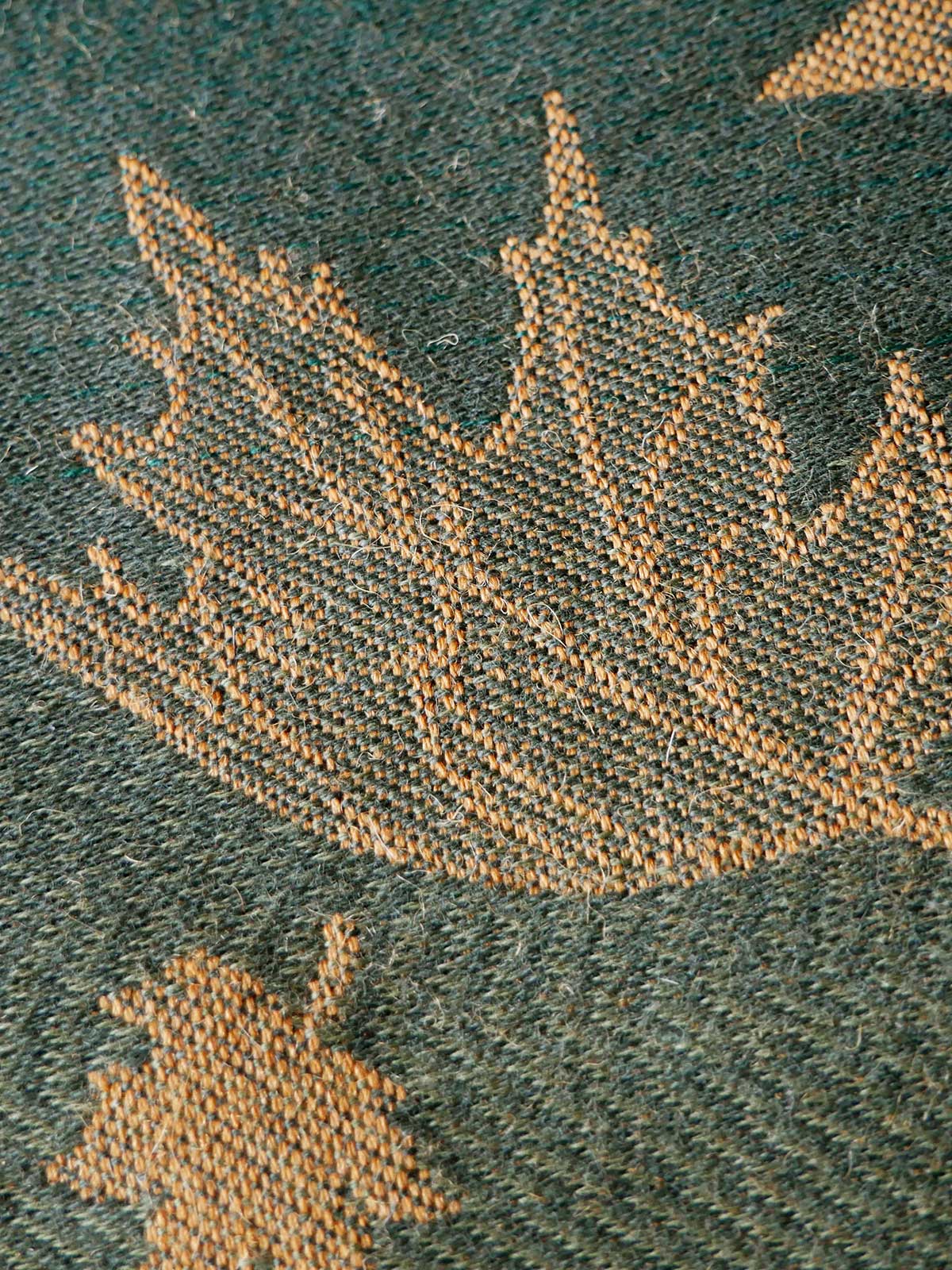 Close-up of a textured fabric with leaf patterns on a green background