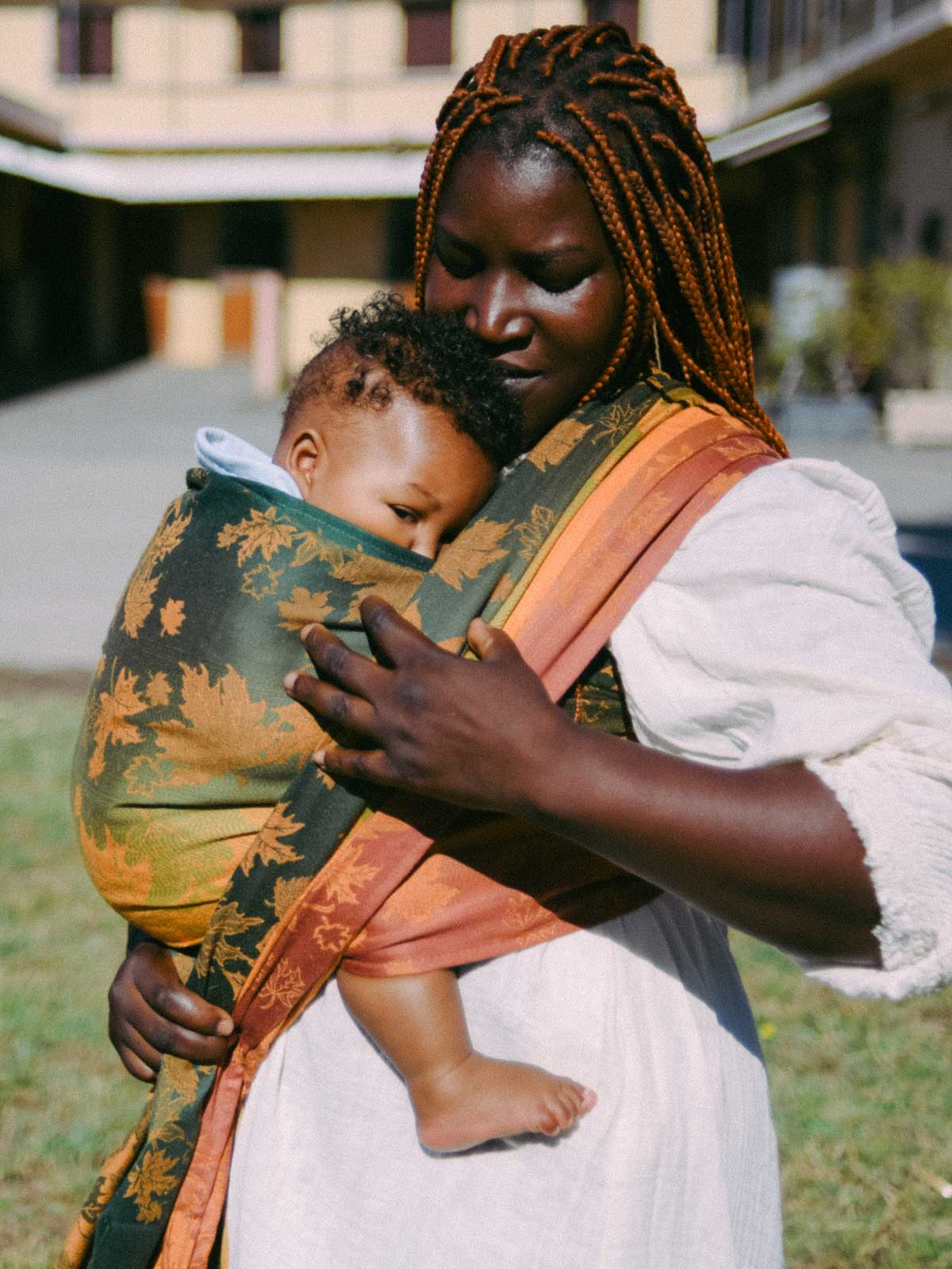 Woman holding a baby in a sling outdoors