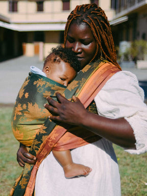 Woman holding a baby in a sling outdoors