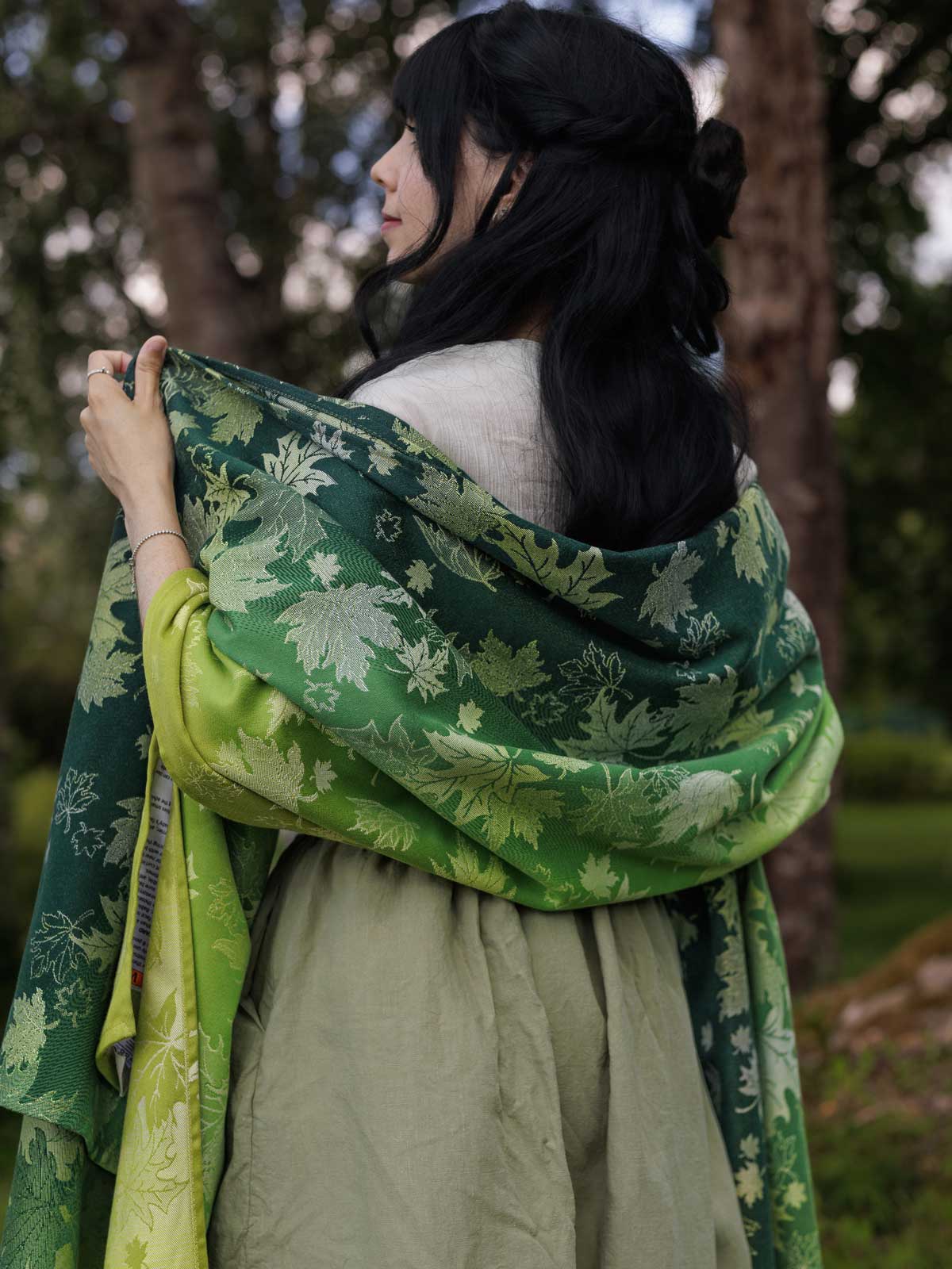 The back of a woman wearing a green shawl with a leaf pattern.