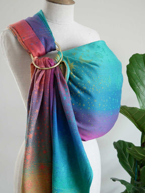 Colorful baby sling on a mannequin with a plant in the background