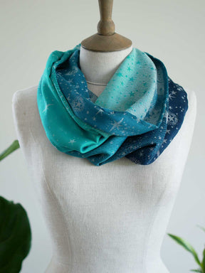 Front view of blue and teal cowl with starry pattern on a mannequin