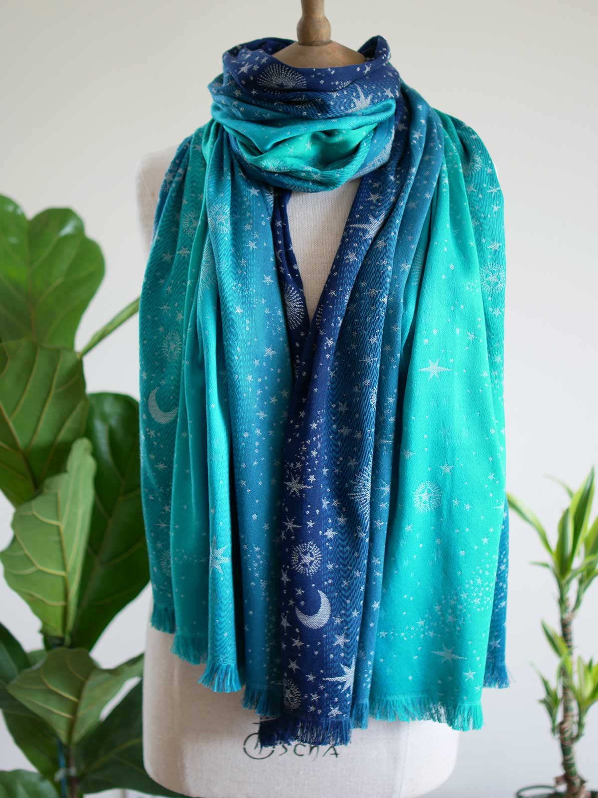 Blue and teal scarf with starry pattern on a mannequin with plants in the background