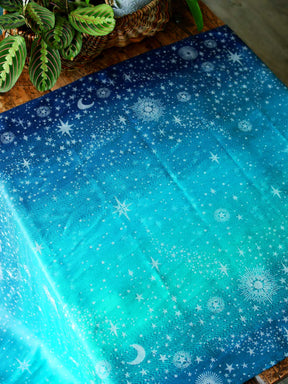 Blue and teal fabric with starry pattern laid flat on a wooden table
