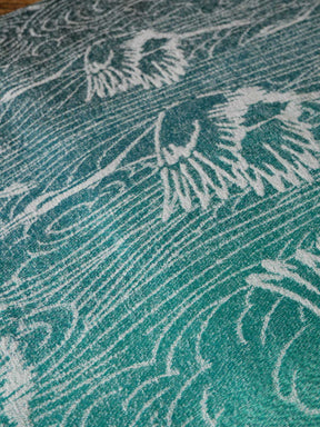 Close-up of a textured teal fabric with white crane patterns