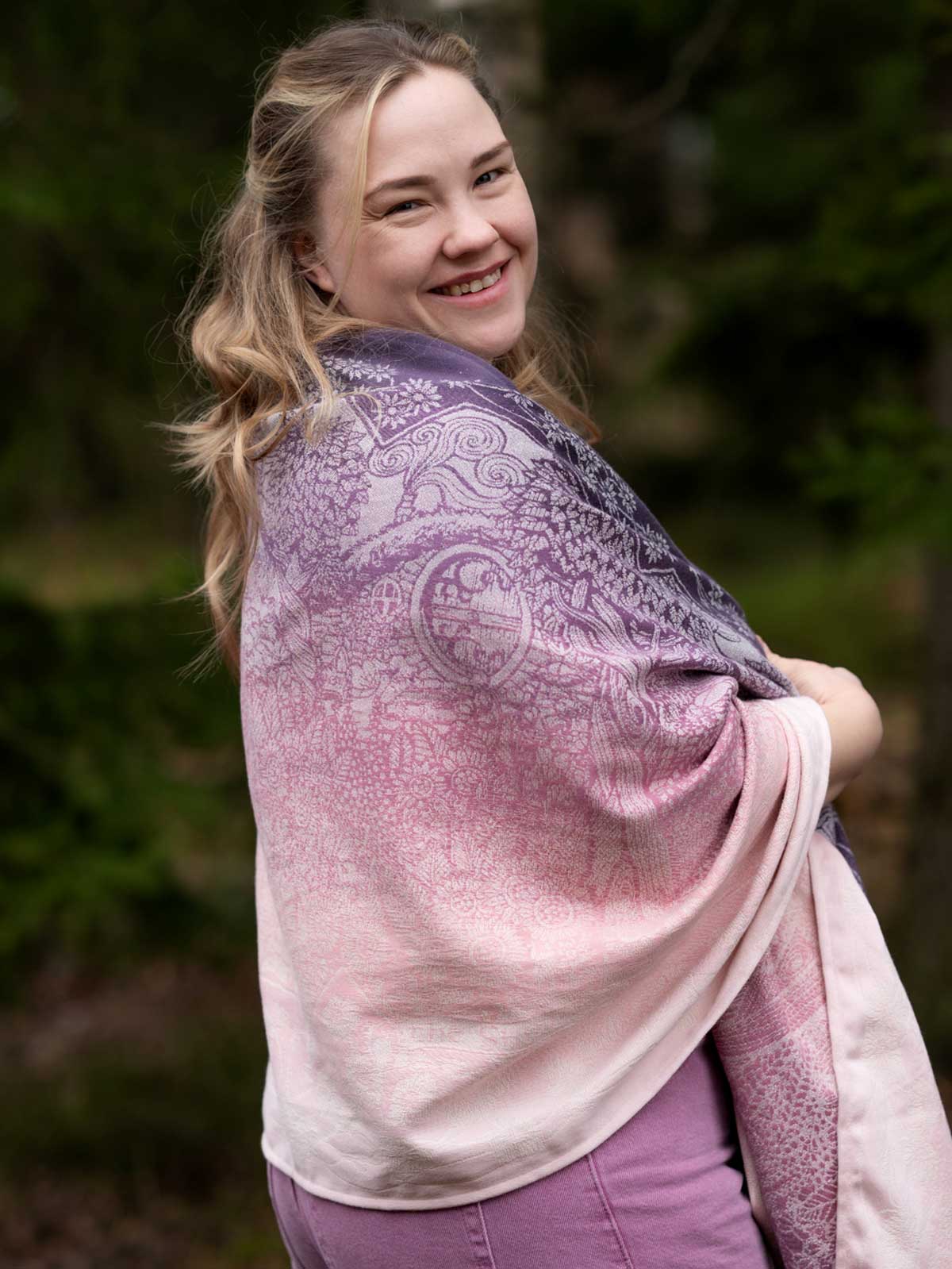 A woman wearing a pinky purple shawl with a Hobbiton pattern