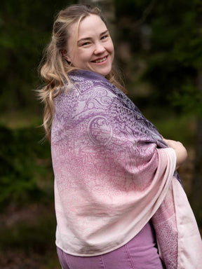 A woman wearing a pinky purple shawl with a Hobbiton pattern