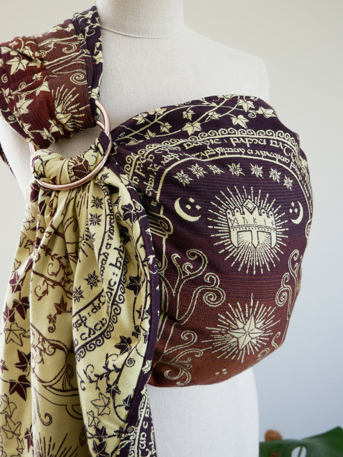 Mannequin wearing a patterned fabric ring sling with Lord of the Ring design on a plain background