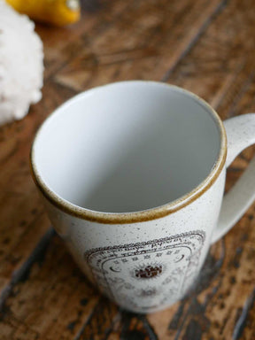 Close-up of a ceramic mug with a decorative rim on a wooden surface