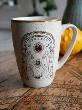 White Middle-earth mug with golddecorative design on a wooden surface