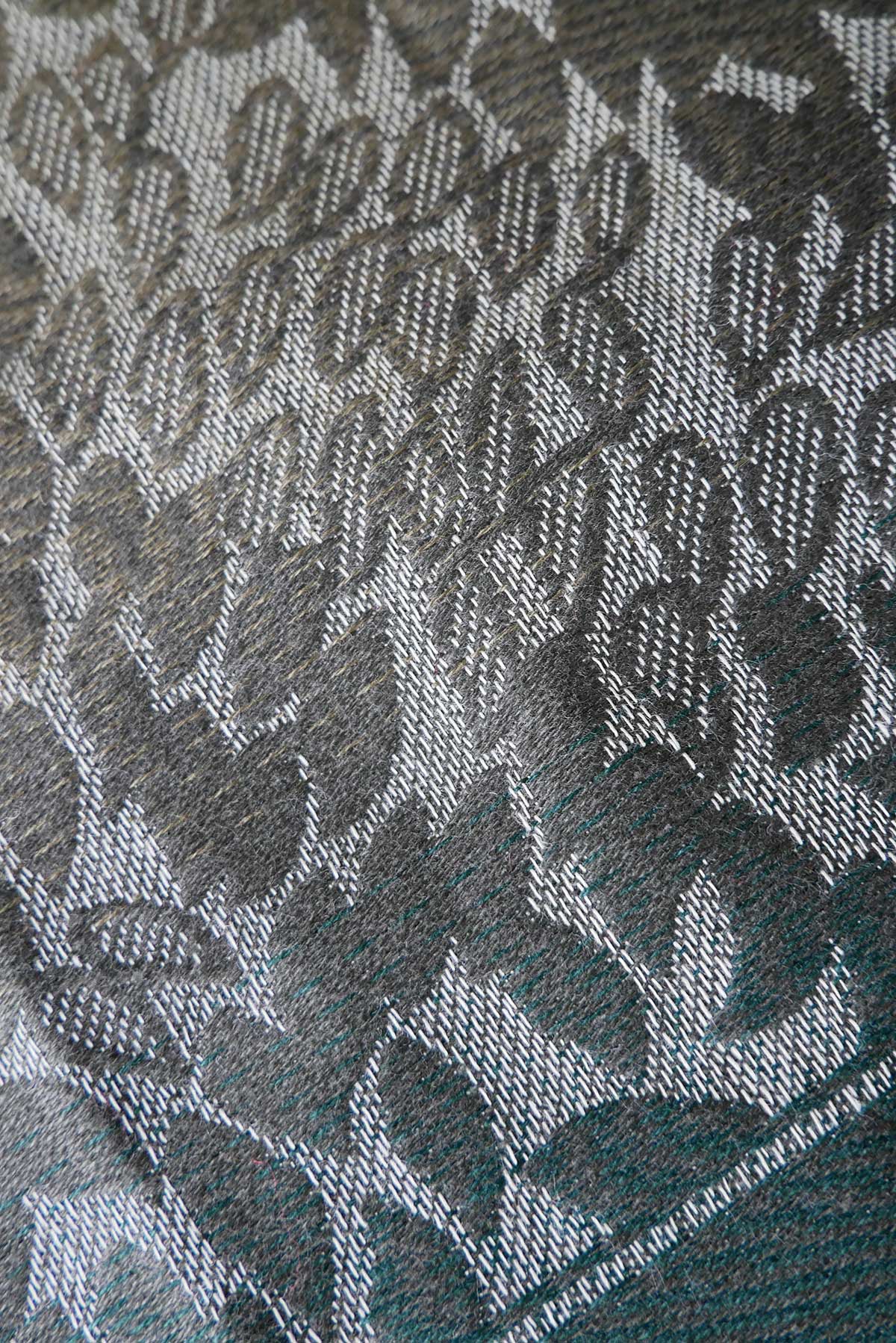 Close-up of a textured fabric with a leaf pattern in green. 