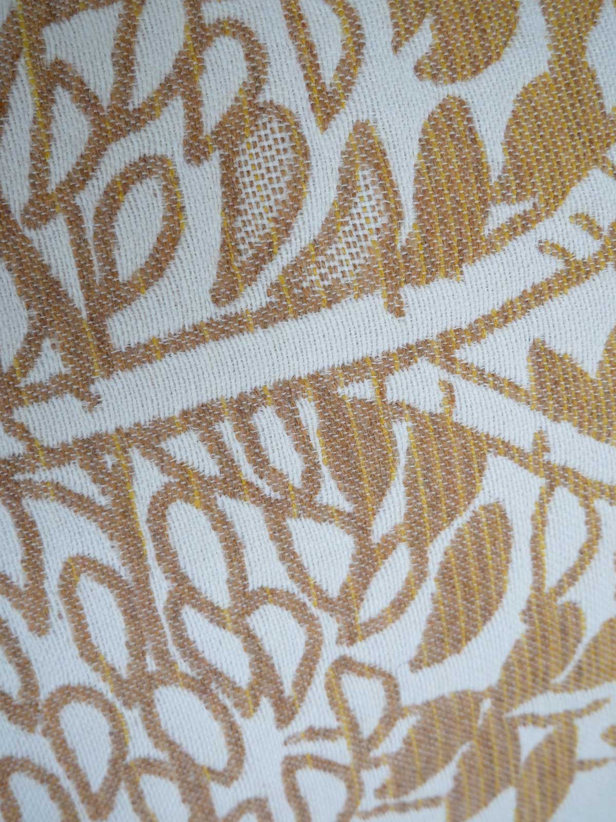 Close-up of a fabric with a gold leaf pattern on a white background