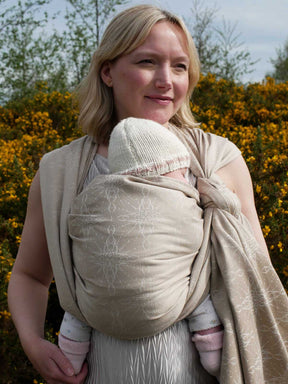 Woman with a baby in a woven wrap with a natural background