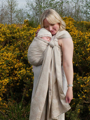 Woman with a baby in a woven wrap with a natural background