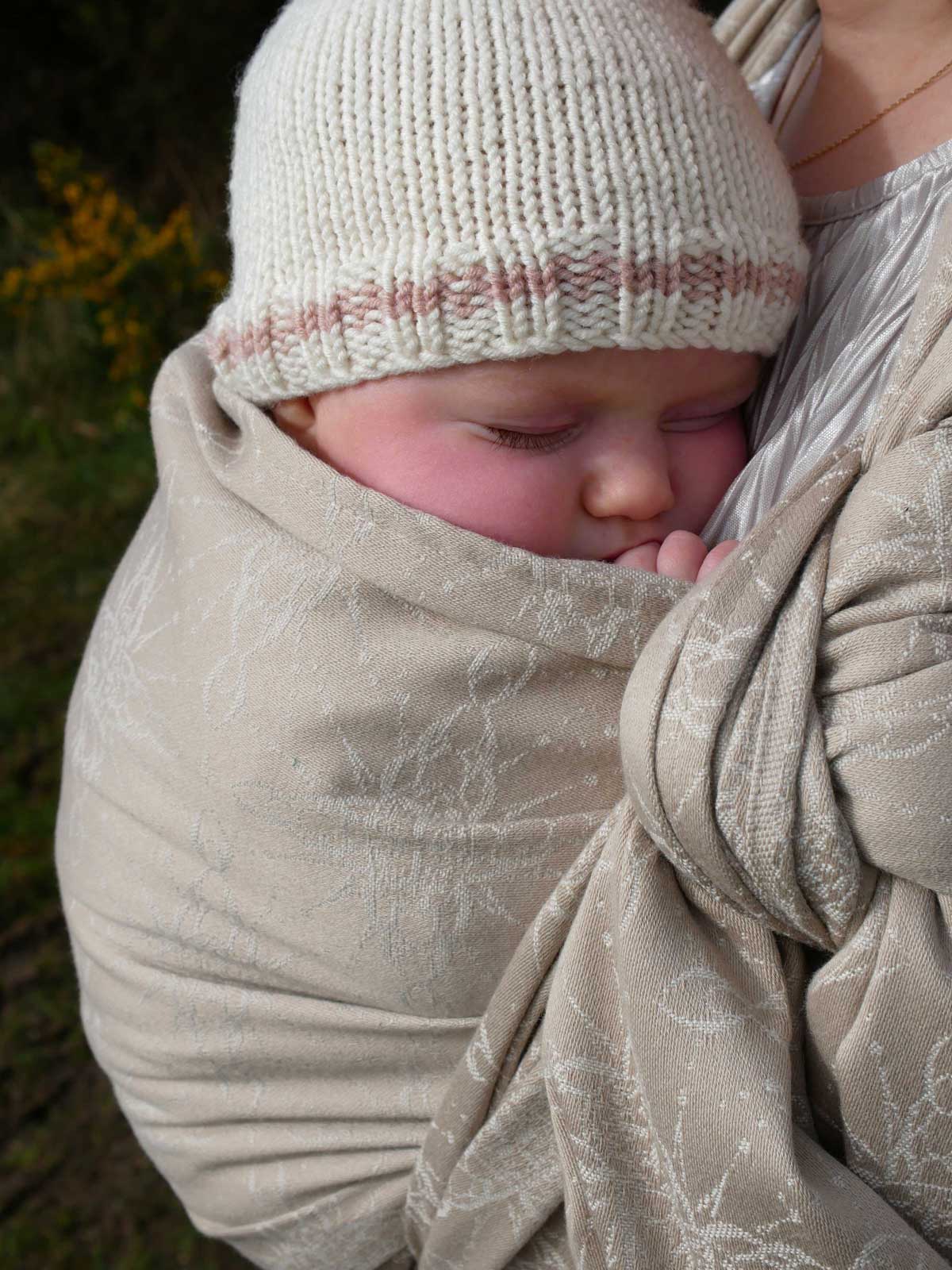 Baby in a woven wrap with a natural background